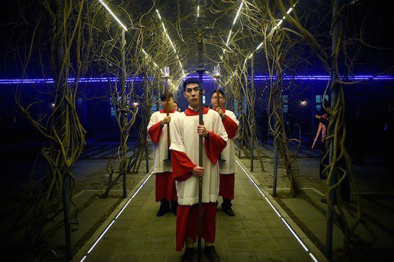A cross-bearers prepares to enter the church as he attends the Christmas Eve mass at a Catholic church in Beijing on December 24, 2015 as Christians around the world prepare to celebrate the holy day. / AFP PHOTO / WANG ZHAO